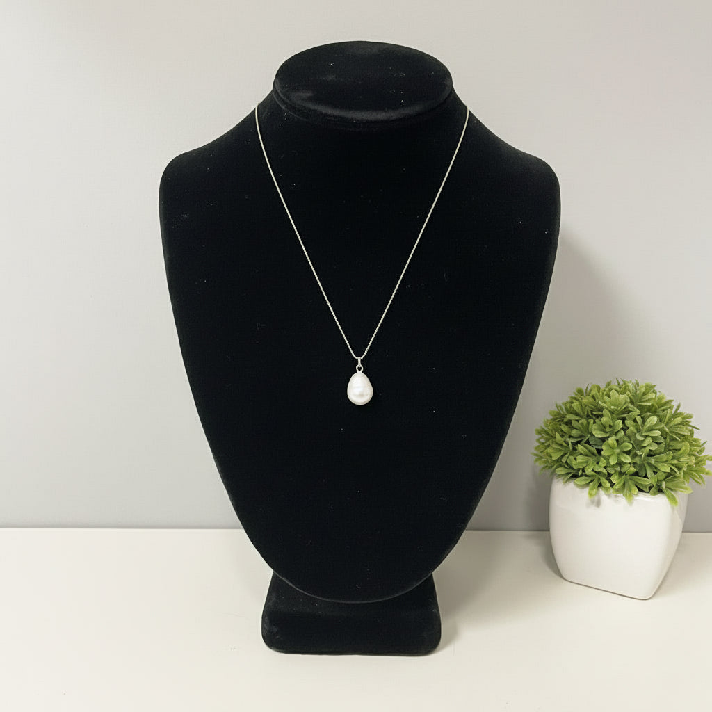 Pearl necklace on a black velvet bust against a plain background