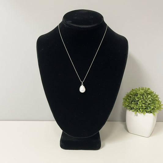 Pearl necklace on a black velvet bust against a plain background